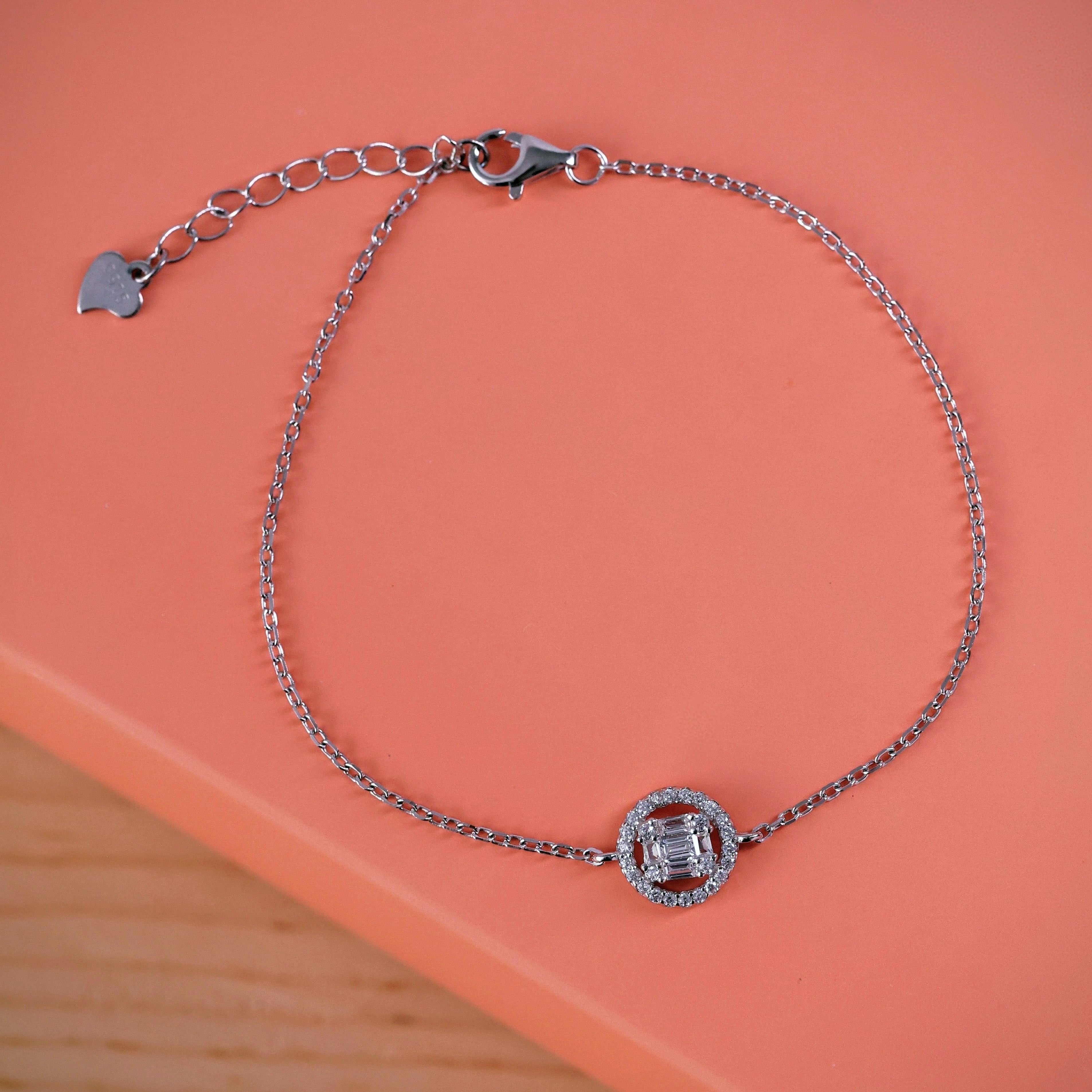 Shop an elegant emerald-cut halo bracelet in sterling silver. Featuring a sparkling centre stone and delicate chain, perfect for everyday wear or gifting.