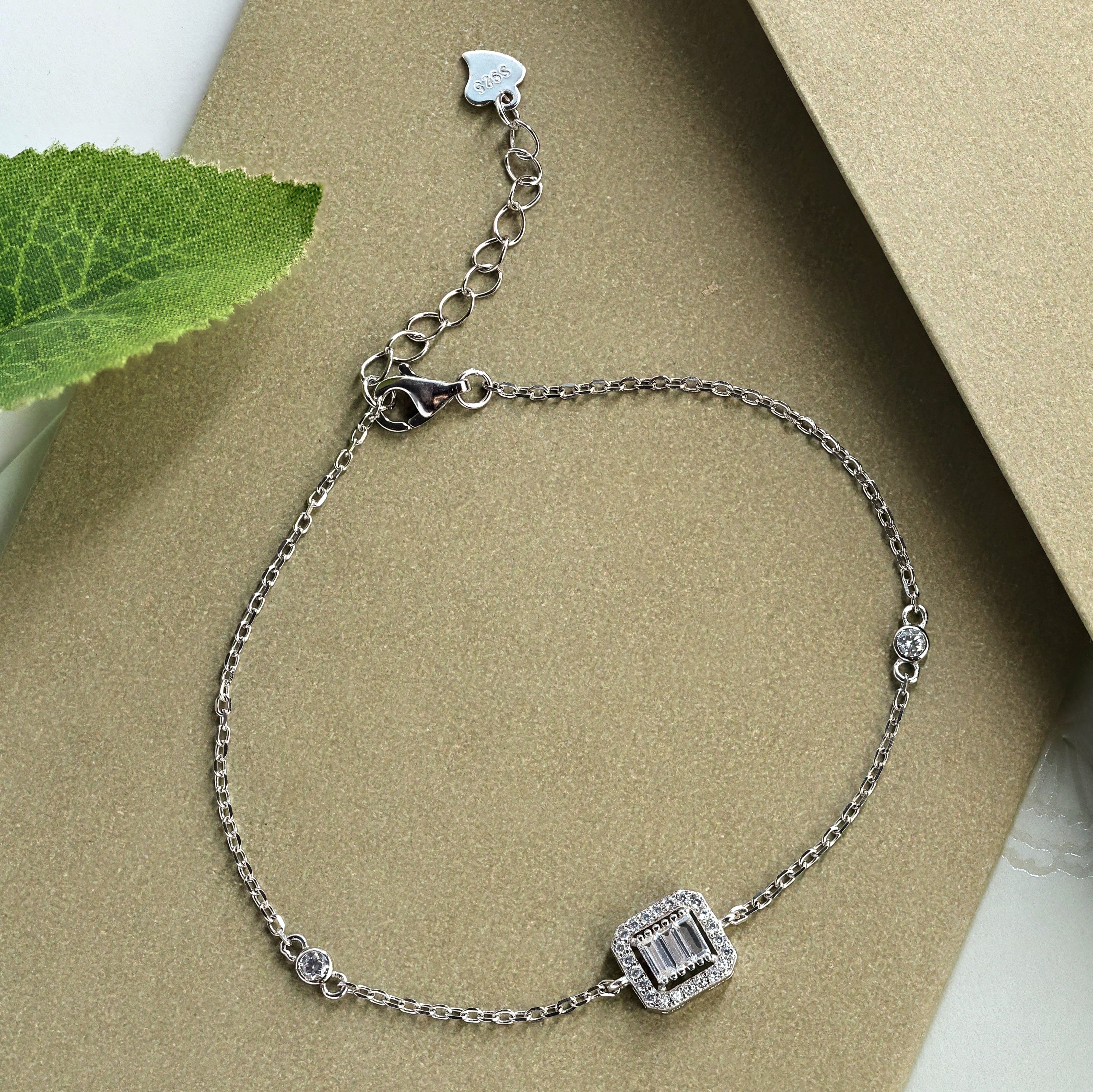 Discover a stunning 925 sterling silver bracelet featuring an emerald-cut centre stone, square halo setting and sparkling accents. Shop online at Sarwana.